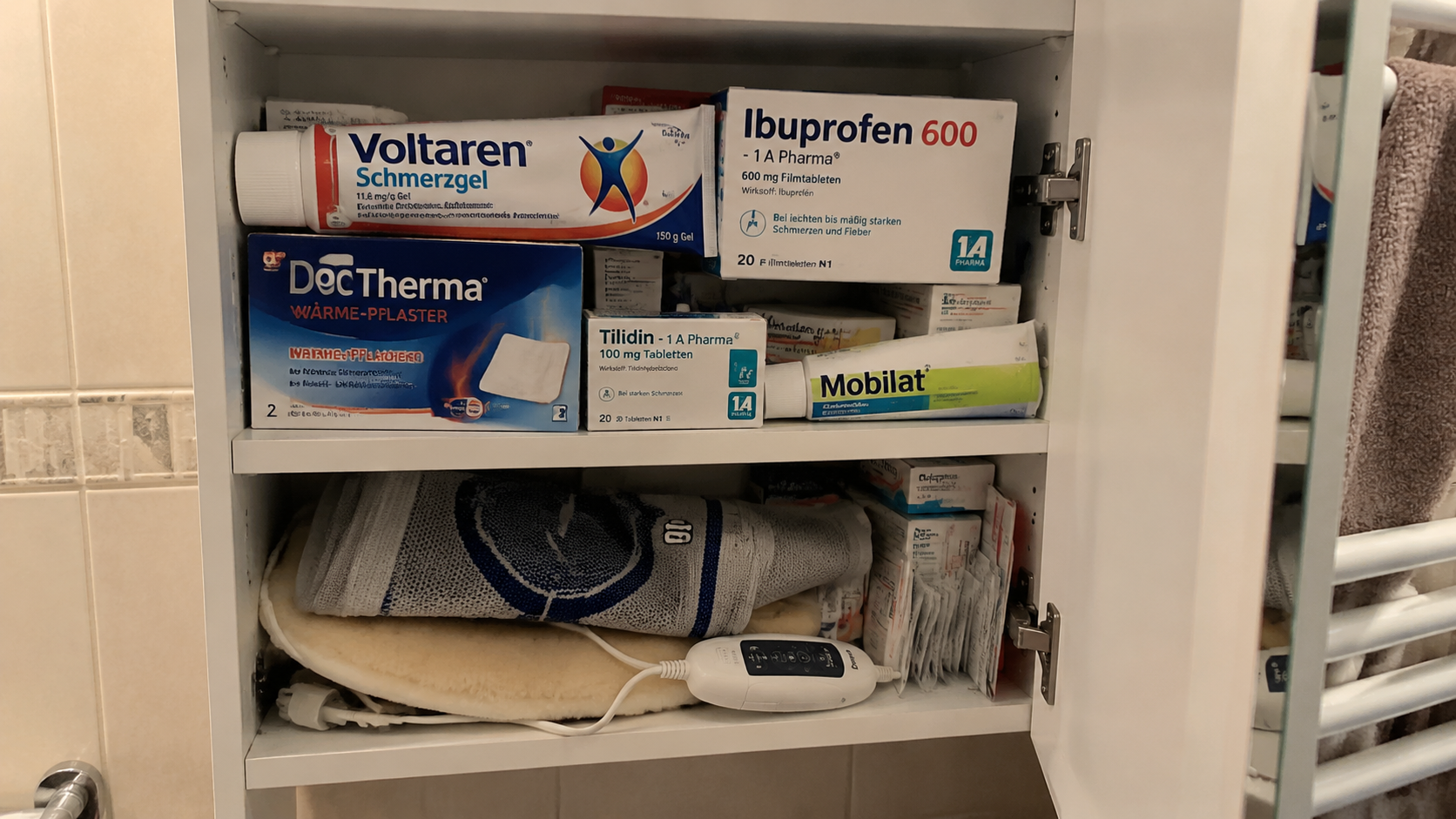Voller Medikamentenschrank mit deutschen Schmerzmittel-Packungen